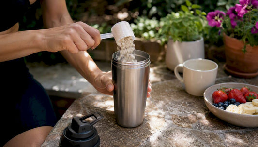 Hands scooping protein powder into shaker